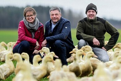 Bernadette, Johann und Markus Forstner inmitten vieler Enten auf einer Wiese